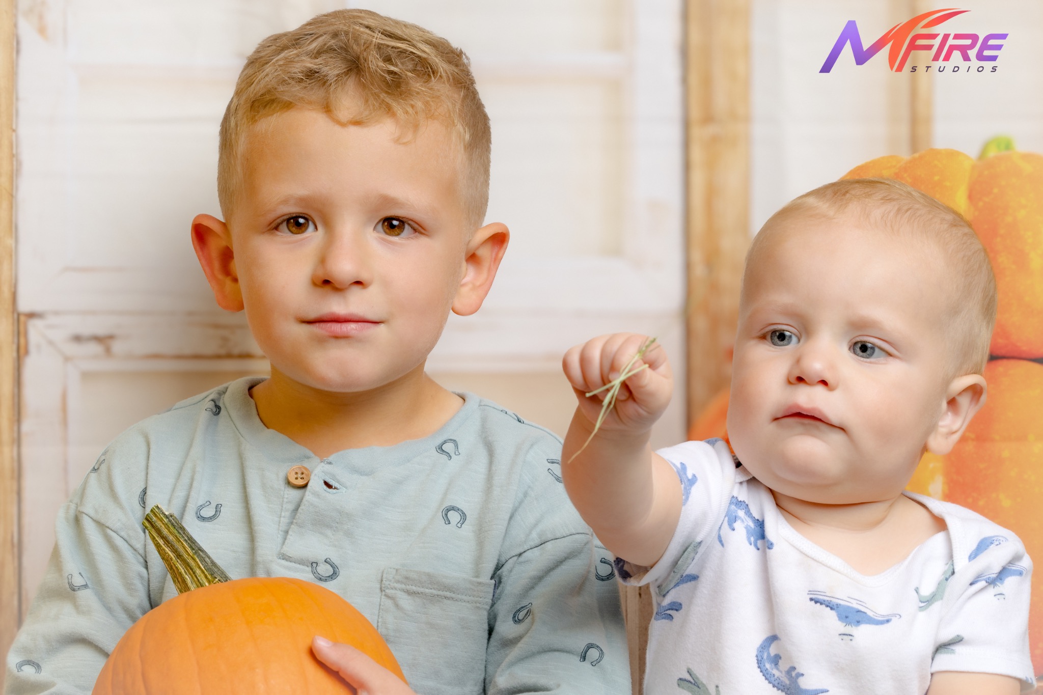 Two children with pumpkins during a fall studio session